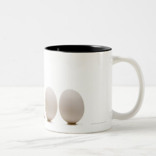 Caneca De Café Em Dois Tons Fim-acima de um pintinho do bebê com três ovos