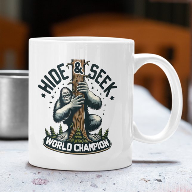 Caneca De Café Engraçado Ocultar e Procurar campeão mundial do Pé (White mug with Bigfoot "Hide & Seek World Champion" design on an outdoor table.)