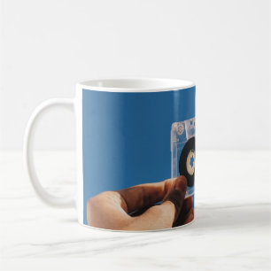 Caneca De Café Pessoa segurando fita cassete branca e preta