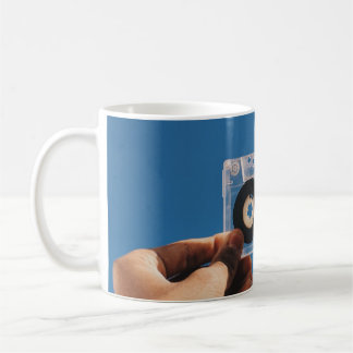 Caneca De Café Pessoa segurando fita cassete branca e preta