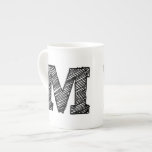 Caneca De Porcelana Mug Monograma: Letra M<br><div class="desc">Caneca monogramada com a letra "M" a preto.</div>