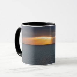 Caneca raios solares do ouro sobre as reflexões do oceano