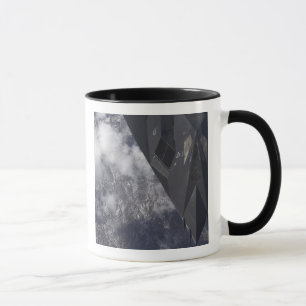 Caneca Um F-117A Nighthawk voa alto sobre a montanha