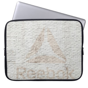 Capa Para Notebook Foto de aproximação do logotipo Reebok na parede