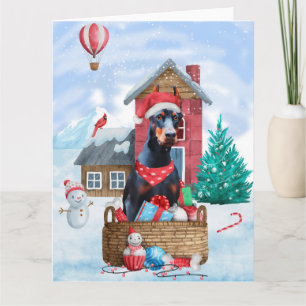 Cartão Cão Doberman na Casa de Natal na Neve