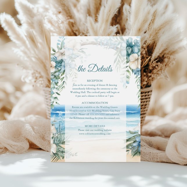 Cartão de Detalhes do Casamento do Arco Floral Azu (Boho Beach Blue Floral Arch Wedding Details Card on a table in front of white pampas grass.)