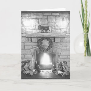 Cartão De Festividades Annice and Margot Belden sitting by a fireplace at