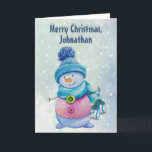 Cartão De Festividades Cute Snowman Holding Christmas Bells, Snowy<br><div class="desc">This customizable card has a cute cartoon style snowman in a scarf and cap. It is holding Christmas bells on ribbons. On a snowy blue gradient background. Inside is a larger image of the bells. The colors are mostly blues and pinks. You can change this text. This card would be...</div>