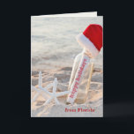 Cartão De Festividades Happy Holidays message in a bottle<br><div class="desc">Happy Holidays message in a bottle with starfish and furry Santa hat on the beach</div>