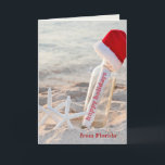 Cartão De Festividades Happy Holidays message in a bottle<br><div class="desc">Happy Holidays message in a bottle with starfish and furry Santa hat on the beach</div>