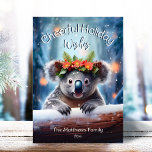 Cartão De Festividades Koala Bear Snowy Winter Forest Feliz Natal<br><div class="desc">Esta adorável carta de cartões de natal apresenta uma ilustração fofa do Urso Koala vestindo uma coroa festiva de flores de inverno, sagradas, pinheiro e bagas, com flocos de neve suavemente caídos contra o fundo da Floresta de Neve e Inverno. O pequeno Urso Koala está espreitando sobre o tronco de...</div>