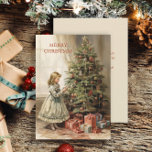 Cartão De Festividades Presentes de natais vintages de Árvore<br><div class="desc">Cartão de saudação de Natal com uma pintura de vintage de uma menina decorando uma árvore de Natal com presentes embrulhados por baixo. O texto diz, "Feliz Natal" mas é personalizável para sua própria saudação. Personalizado no verso com sua mensagem e seu nome. Entre em contato comigo para obter assistência...</div>