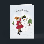 Cartão De Festividades Snowman e Little Girl Christmas Card<br><div class="desc">Menina num casaco vermelho brilhante colocando um chapéu preto num boné de neve.</div>