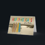 Cartão de Natal com surfboards Vintage em Beach<br><div class="desc">Uma criação gráfica nostálgica para este cartão de Natal Merry, com conselhos antigos, de aparência antiga, em pé contra um lugar de madeira rústico na areia com o oceano a distância. Cartas em negrito soletrando Feliz Feriados e as luzes de férias são tiradas sobre eles. Cartão de Excelente para surfista...</div>