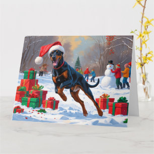 Cartão Doberman Correndo na Neve com Chapéu de Natal