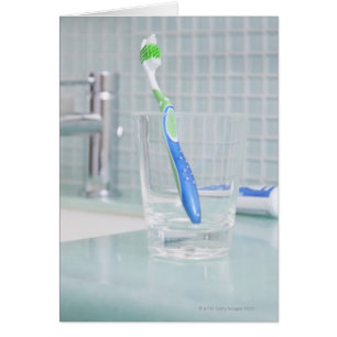 Cartão Escova de dentes em uma xícara no banheiro