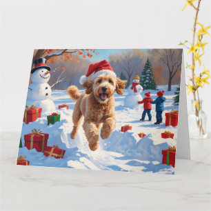 Cartão Goldendoodle correndo em neve com chapéu de Natal