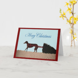 Cartão Greyhound puxando uma árvore de Natal pela neve