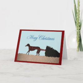 Cartão Greyhound puxando uma árvore de Natal pela neve
