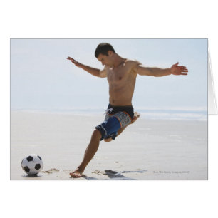 Cartão Homem que retrocede a bola de futebol na praia