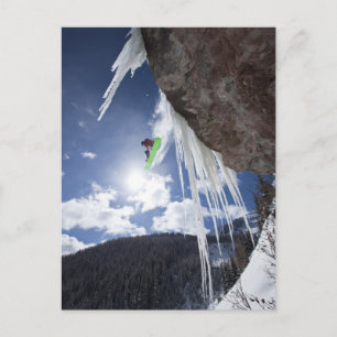 Cartão Postal A male snowboarder jumps off an ice waterfall