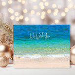 Cartão Postal De Festividades Ocean Beach Deseje Feliz Natal<br><div class="desc">Cartões postais de Natal com cena oceânica e praia. Personalize com sua saudação e assinatura. Água azul tropical e areia de praia na frente com um texto de amostra, "nós desejamos" (mude o texto para "I", conforme necessário). O texto continua atrás com uma saudação de "Feliz Natal" e "Feliz ano...</div>