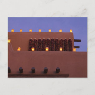 Cartão Postal Farolitos tradicionais iluminam estruturas de adob