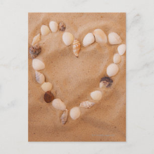 Cartão Postal Fechar a forma cardíaca feita de conchas na areia