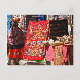 Cartão Postal Mulher indiana peruana olhando têxteis coloridos
