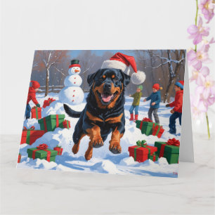 Cartão Rottweiler correndo em neve com chapéu de Natal