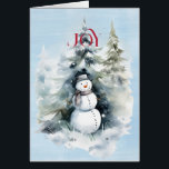 Cartão Snowman in the Forest com Red JOY<br><div class="desc">Uma bela imagem de um boneco de neve na floresta,  com uma alegria vermelha que te atinge. Tudo em um fundo de aquarela azul. Dentro é FÉRIAS FELIZES em vermelho e melhores desejos para o Ano Novo em preto</div>