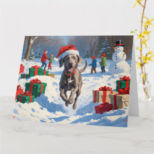 Cartão Weimaraner Correndo na Neve com Chapéu de Natal