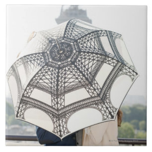 Casal sob um guarda-chuva com a torre Eiffel