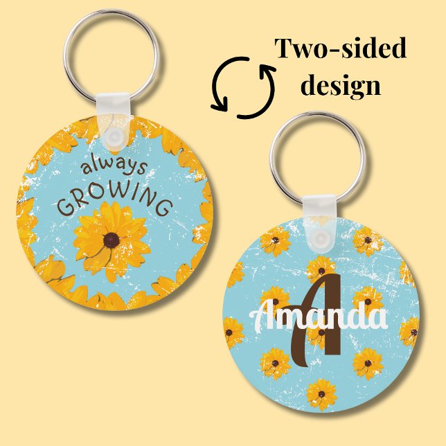 Chaveiro Flor Amarelo Russo Robin Ovo Azul Sempre Crescendo (Sky blue round metal keychain with yellow flowers features a spot for a first name and initial.)