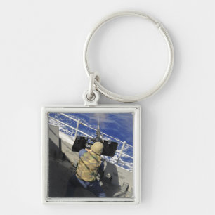 Chaveiro Gunners Mate disparando uma metralhadora calibre 5