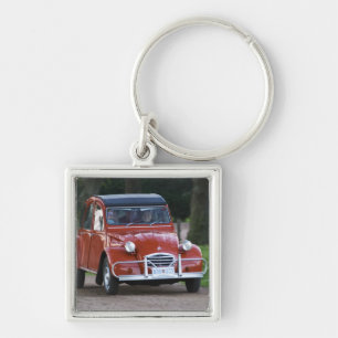 Chaveiro Um velho Citroen 2CV vermelho com uma mulher sorri