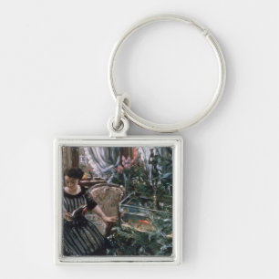 Chaveiro Uma mulher que lê perto de um tanque do peixe