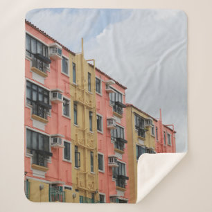 COBERTOR SHERPA EDIFÍCIO DE CONCRETO AMARELO E VERMELHO SOB NUVEN