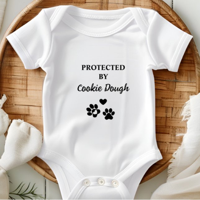 Cuja proteção é personalizada por cão (Adorable baby bodysuit with "Protected by (Dog's Name)" design, featuring hearts and paw prints.)