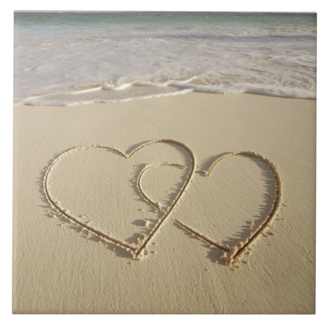 Dois corações sobrejacentes tirados na praia com (Frente)