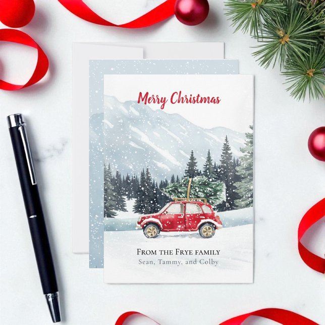 Festividades Cartão de Férias de Montanha da Árvore de Natal do (Christmas holiday red car with Christmas tree on a snowy mountain top. Card is on marble countertop)