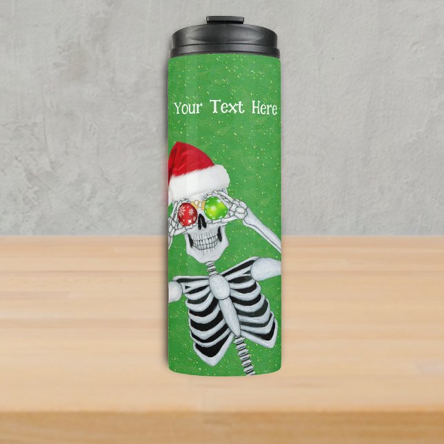 Garrafa Térmica Bobo Natal Esqueleto Ornaço Olhos Verdes Dourados (Funny Christmas skeleton Santa Hat Ornament eyes on green with gold specks thermal drink tumbler.)