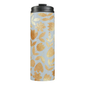 Garrafa Térmica Douradas flores, fundo azul, imitação de folhas.
