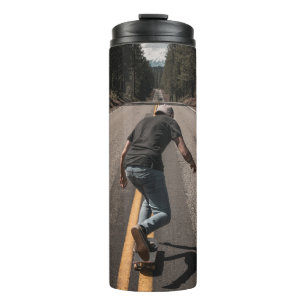 Garrafa Térmica Homem jogando skate na estrada pela manhã