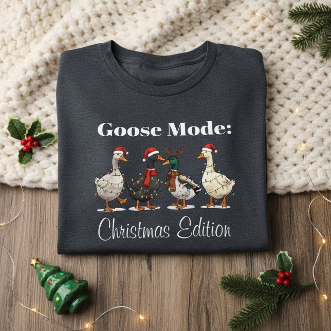 Goose Mode Christmas Edition T-Shirt (folded dark gray Christmas shirt with goose design on cozy knit blanket and festive decor)
