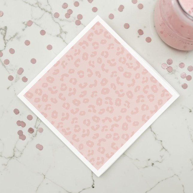 Guardanapo De Papel Estampa de Leopardo em Rosa (A pink leopard print napkin on a white marble countertop with muted pink confetti and a pink drink.)