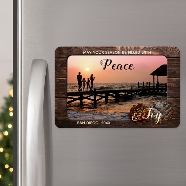 Ímã Magnet de Fotografia de Férias Personalizadas da M (A Christmas magnet featuring your custom photo framed by rustic dark wood and festive pine cone)