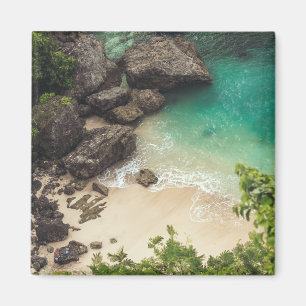Imã Sandy Beach Cove com árvores verdes, rochas e oce