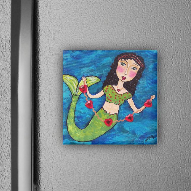 Imã Sereia Com Magneta De Corações (Mermaid green tail holding gold string of red heats on ocean blue magnet.)