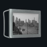 Kansas City Urban Skyline, foto em preto e branco<br><div class="desc">Em Kansas City, Missouri, a rua principal de seis pistas se estende do canto inferior direito da fotografia branca e preta em direção ao horizonte de arranha-céus sujo a distância. Um sedan escuro, abaixo e à esquerda do centro, dirige perpendicularmente às faixas de tráfego criando um momento de intrigação na...</div>
